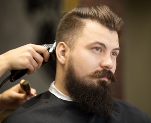 bearded man receiving a haircut